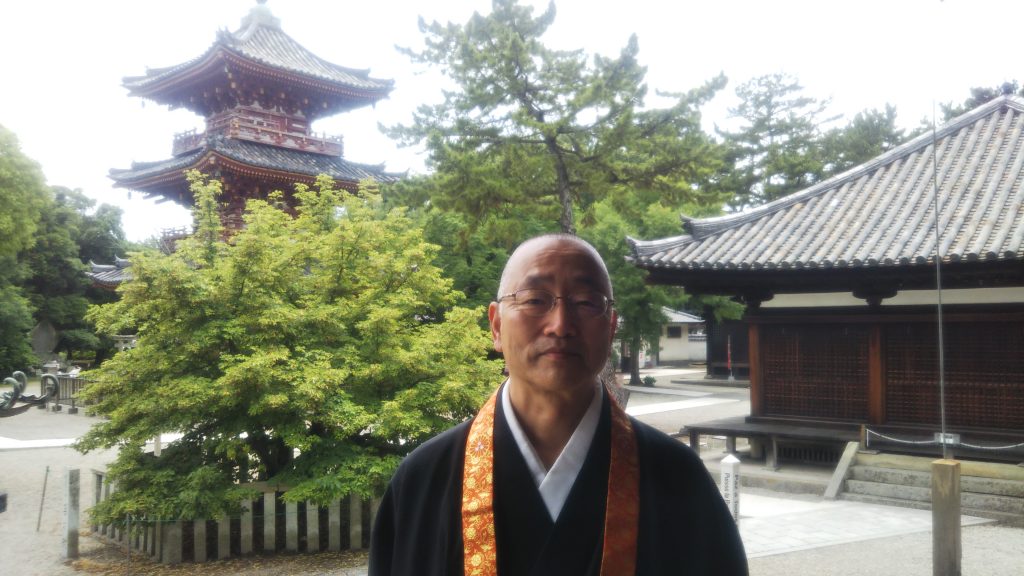 三重塔と菩提樹をバックに 茂渡俊慶住職「沙羅の花は落ち込んだ心を癒してくれる」